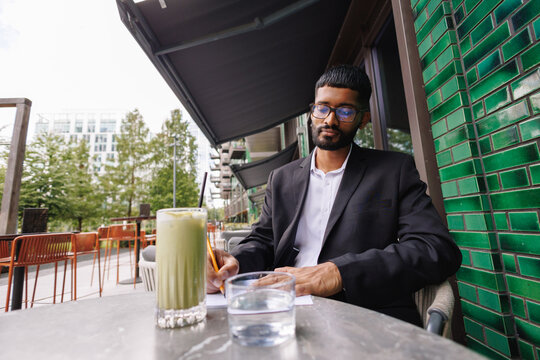 Young businessman writing at outdoor city cafe