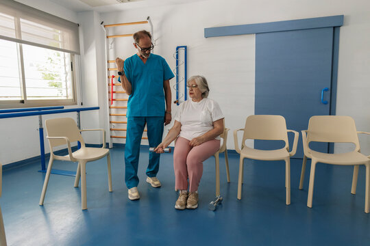 Senior woman exercising with physiotherapist in rehabilitation center