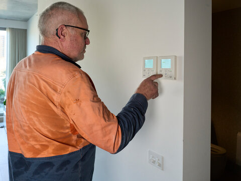 Aircon Tech Adjusts Temperature Controls inside home
