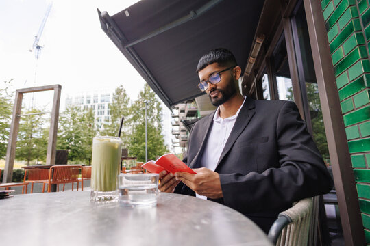 Young businessman reading book at outdoor cafe