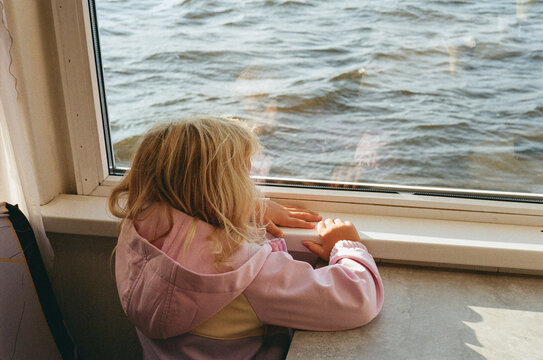 Child Looks out of a Window at Water on a Boat Ride