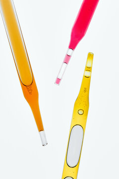 Laboratory Glass Pipettes with Colorful Liquids on Light Background.