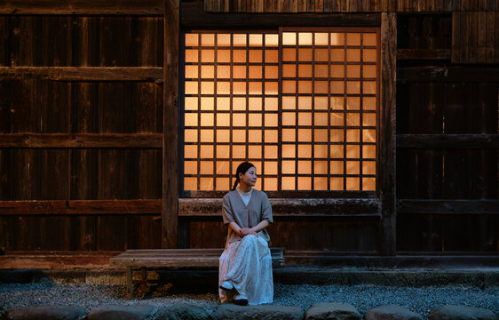 Zen Night: Woman Sitting by a Lit Temple Paper Window