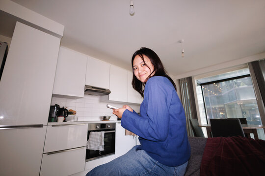 Filipina woman smiling and texting in London apartment