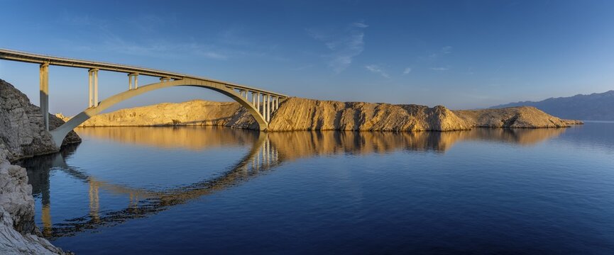 Pag bridge over calm water in soft morning light with clear reflections, Pag, Zadar, Croatia