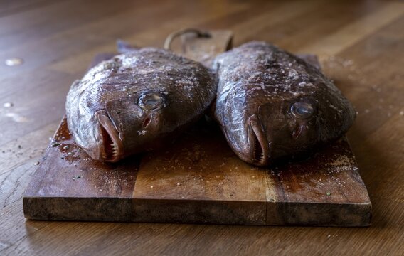 Two bream lying on a wooden board on a kitchen counter, ready for preparation, Zadar, Croatia