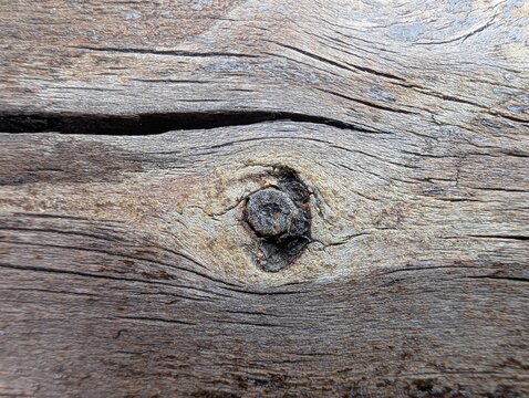 Weathered wood grain with a dark knot and swirling lines, etched by