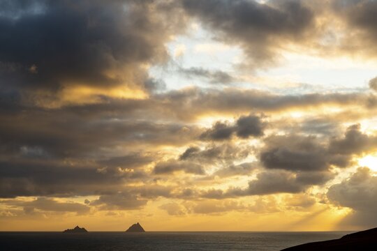 Seashore with the mountain peaks of the Skelligs in the background and dramatic cloudy sky, Killarny, County Kerry, Ireland
