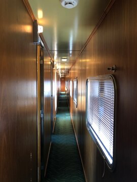 View along the narrow vintage wood-paneled corridor of a luxury sleeper train