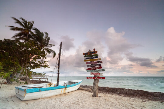 Colourful directional beach sign and fishing boat on  tropical sandy beach, Punta Cana, Dominican Republic