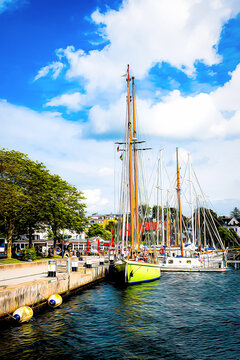 Several sailing ships are moored at the quay wall in the harbor of Laboe on the Baltic Sea &ndash; depicted as a cartoon illustration.