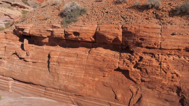 Panning shot across red sandstone formation with distinct layers and textures, basking in the bright sunlight of desert canyon in american southwest, revealing geological history