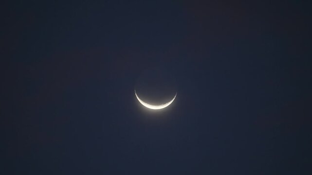 Waxing crescent moon in the dark night sky. Astronomy, outer space, and a minimalist night background.