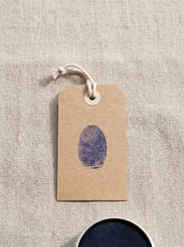 Ink thumbprint on blank kraft paper tag, human made mark