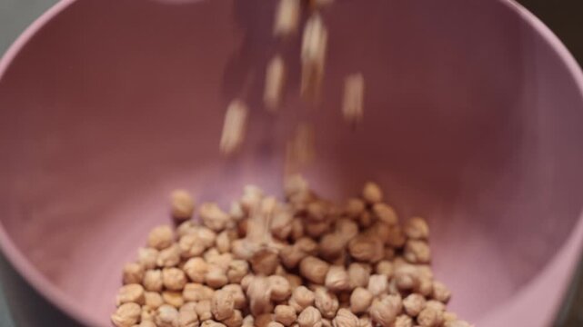Stockholm Dried chickpeas are poured into a pink kitchen bowl. 