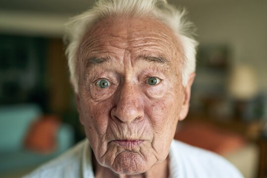 Senior man with raised eyebrows and pursed lips in living room