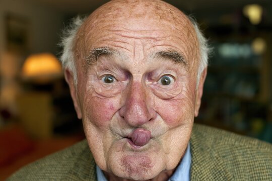 Senior man making cheeky face with puckered lips indoors