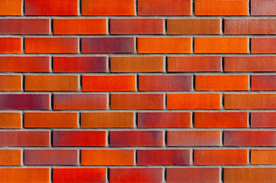 Seamless vibrant red and orange brick wall background texture pattern of modern clinker tile building facade surface