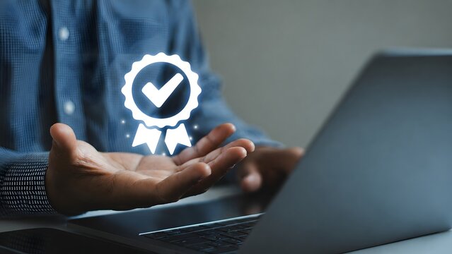 Businessman hand presenting quality certification checkmark icon above laptop, representing approval, trust, compliance, verification, assurance concept for corporate standards professional services.