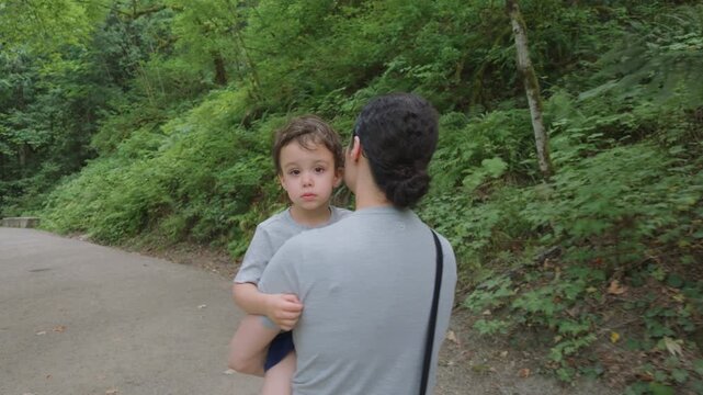 Mother Carries Her Young Son Through the Lush Forest Trails of Othello Tunnels in Hope, British Columbia, Canada