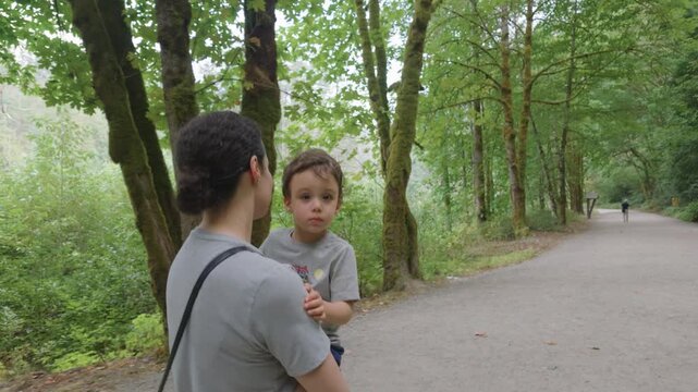 Mother Carrying Son on a Scenic Trail Through Othello Tunnels Park in Hope, British Columbia, Canada