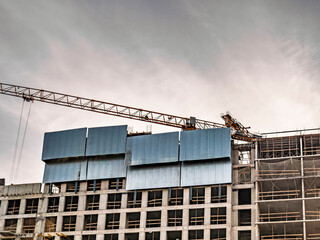 High rise residential building under construction with yellow tower crane against cloudy sky. Modern concrete construction site and engineering. © LemPro Filming Life