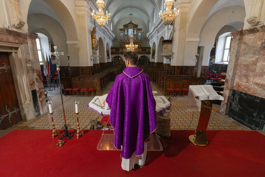 A parish priest stands at the altar in a catholic church leading worship during holy mass. The ceremony takes place in a vibrant setting.