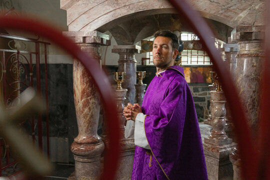 A catholic priest stands in a church ready to conduct a holy mass wearing liturgical vestments. The setting includes religious symbols.