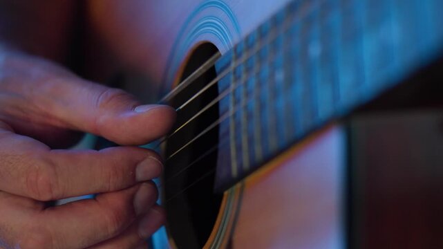Man playing acoustic guitar close up in slow motion, musician fingers plucking strings on fretboard, online music lesson and education concept, guitar practice, tutorial learning and skill development