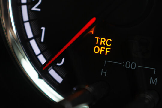 Close-up active TRC OFF traction control warning light on car dashboard gauge