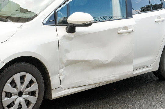 White car door dented, shows minor accident damage