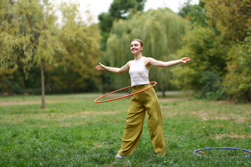 Athletic young woman exercising with hula hoop in park © New Africa