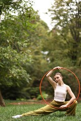 Athletic young woman posing with hula hoop in park, space for text © New Africa