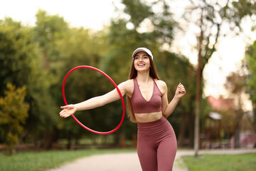 Athletic young woman exercising with hula hoop in park © New Africa