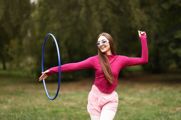 Athletic young woman exercising with hula hoop in park © New Africa