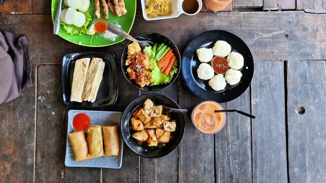 Top View of Authentic Indonesian Food Assortment Featuring Beef Rendang, Fried Rice, and Traditional Snacks on a Rustic Wooden Background