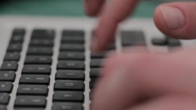 Hands typing on a laptop computer keyboard in a close up view with video person using fingers type laptop keyboard