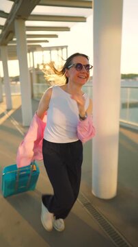 Happy woman pulling a suitcase and running, late for flight. 
