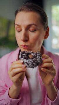 Woman eating a donut and looking around to make sure no one is watching