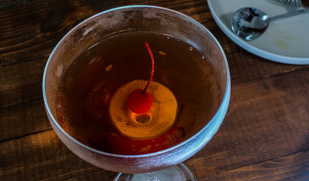 Manhattan cocktail in coupe glass on wooden bar
