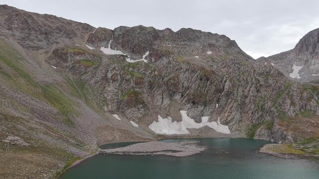 4K Aerial View of a High Mountain Lake Surrounded by Rocky Peaks.