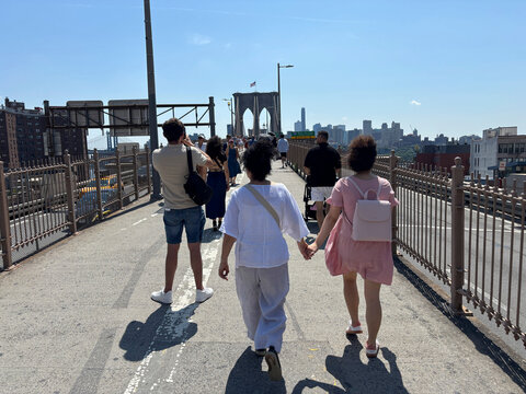 Walkers crossing the Brooklyn Bridge towards Manhattan on the upper promenade, New York, United States