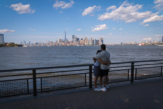 Couple hold each other facing the Manhattan skyline from Liberty Island, New York, United States