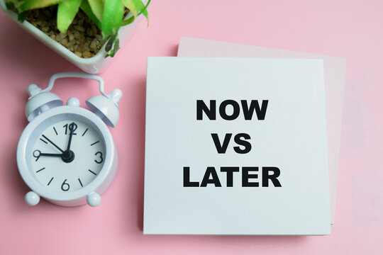 Concept of now vs later write on sticky notes isolated on table.