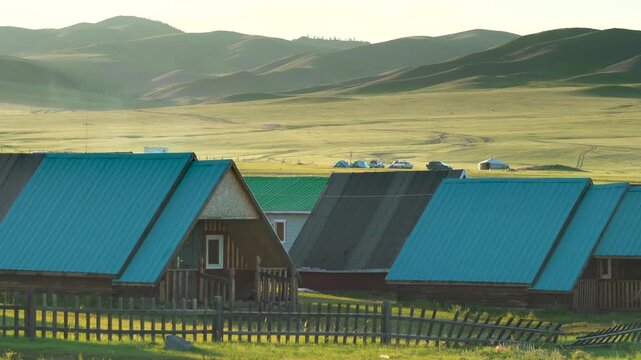 Blue roofed wooden village houses stand on open land in northern mongolia under wide skies.