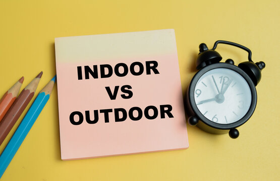 Concept of indoor vs outdoor write on sticky notes isolated on table.