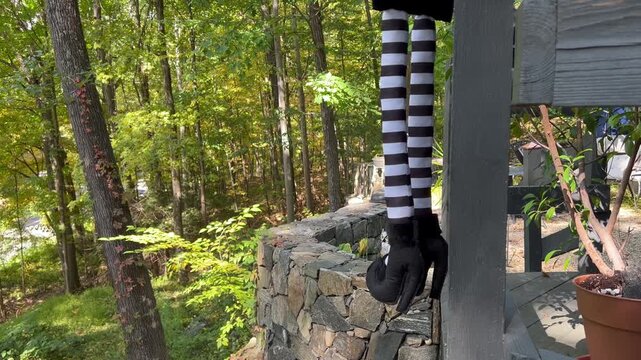 Witch leg decoration dangling outdoors on a wooden deck during autumn