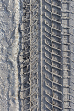 Detailed close up texture of a heavy vehicle tire tread mark impressed into wet dirt. Displays raw outdoor off-road travel details