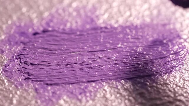 Purple paint brush close-up on a sparkling textured surface