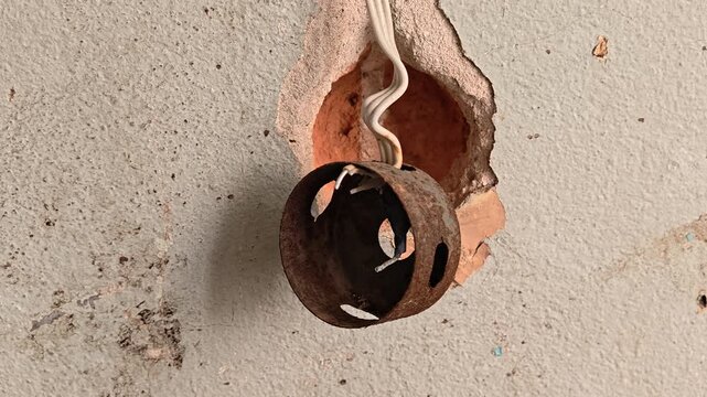 old electrical socket hanging on the wall on a wire